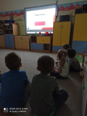 Dzieci oglądają prezenetację o Polsce z Misiem Pysiem.