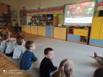 Dzieci oglądają prezentację o pomaganiu w okresie świątecznym.