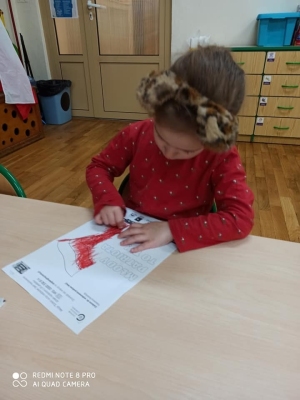 Dziewczynka koloruje flagę Polski.