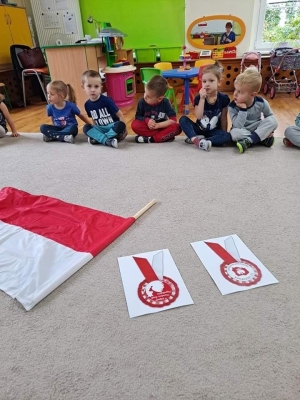 Dzieci oglądają flagę Polski i kotyliony.