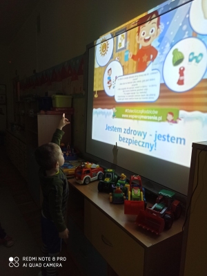 Chłopiec pokazuje symbol na prezentacji.