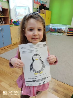 Dziewczynka pokazuje zrobione zadanie - pingwinek.
