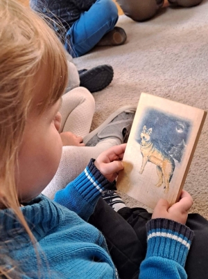 Dziewczynka ogląda obrazek wilka.